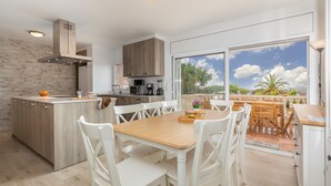 A modern kitchen with a large island, white chairs, and a dining table. - Villa "Terrassa" close to the Beach with Pool & Wi-Fi (Calonge)