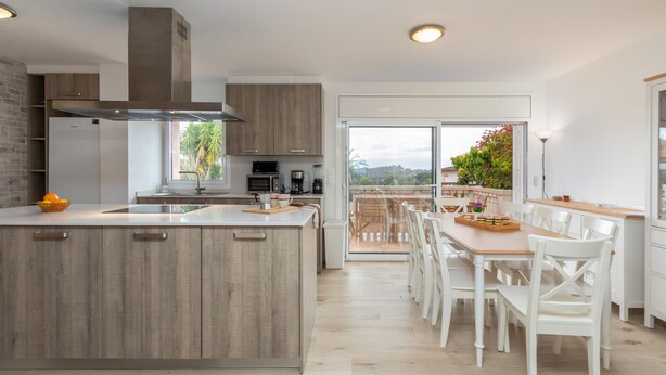 A modern kitchen with a central island, wooden cabinets, and a dining area with white chairs. - Villa "Terrassa" close to the Beach with Pool & Wi-Fi (Calonge)