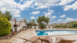 A pool area with lounge chairs, a stone patio, and a white building with a chimney. - Villa "Terrassa" close to the Beach with Pool & Wi-Fi (Calonge)