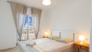 A bedroom with a bed, two bedside lamps, a window with curtains, and a view of a balcony. - Villa "Terrassa" close to the Beach with Pool & Wi-Fi (Calonge)