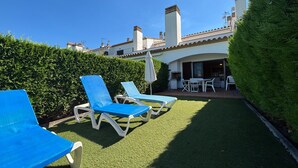 A patio with two blue lounge chairs, a small table, and a white umbrella.