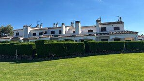 A large, multi-story building with a tiled roof, surrounded by well-maintained hedges and a grassy lawn.