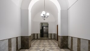 A hallway with a checkered floor, white walls, and a chandelier.