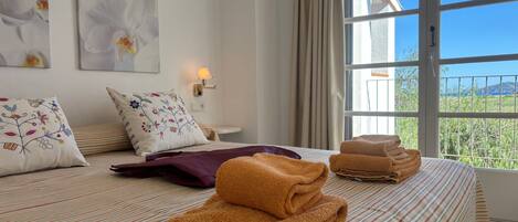 A hotel room with a bed, pillows, a lamp, and a view of the outdoors.