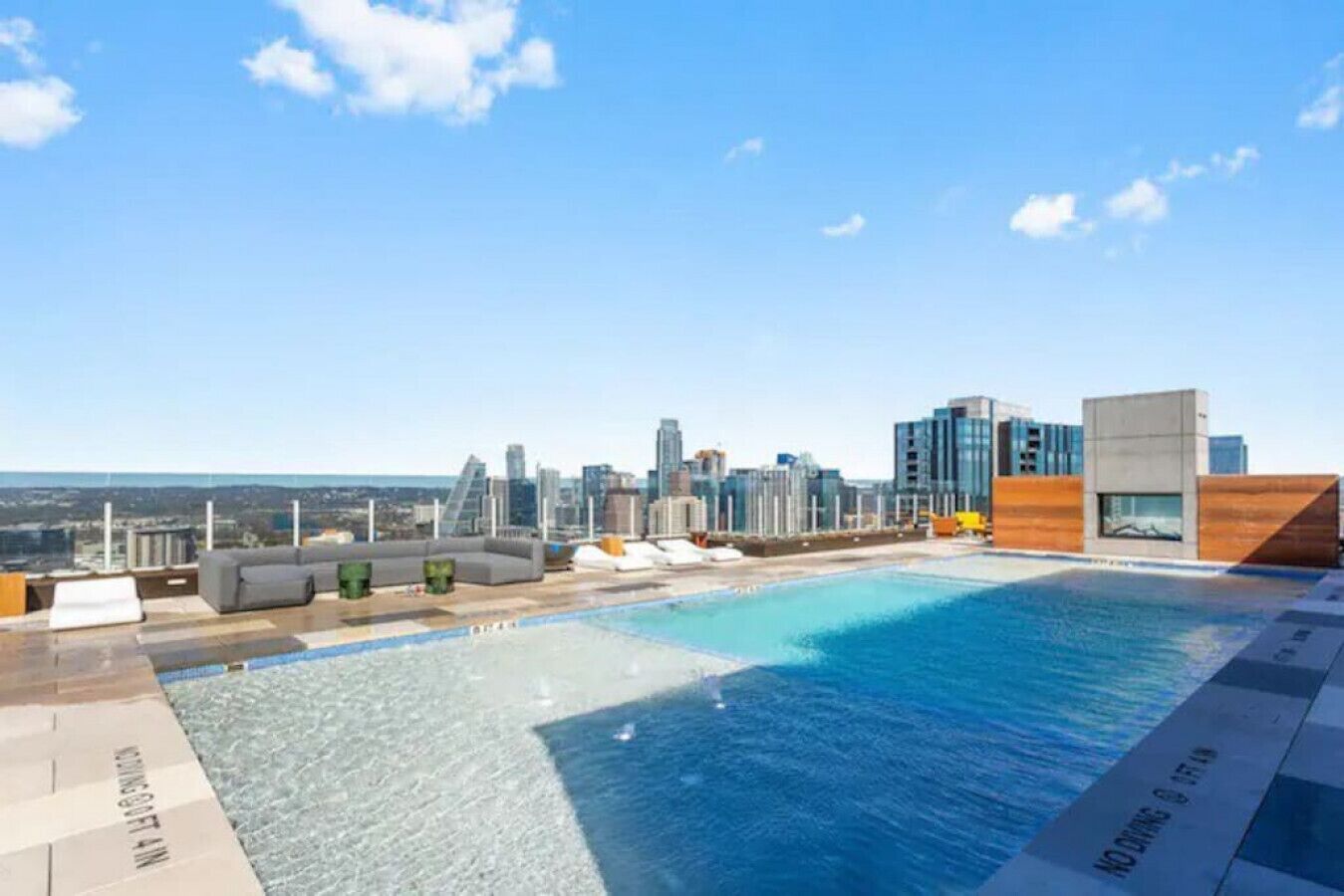 Piscina en la azotea con vista al horizonte urbano, zona de descanso y arquitectura moderna.