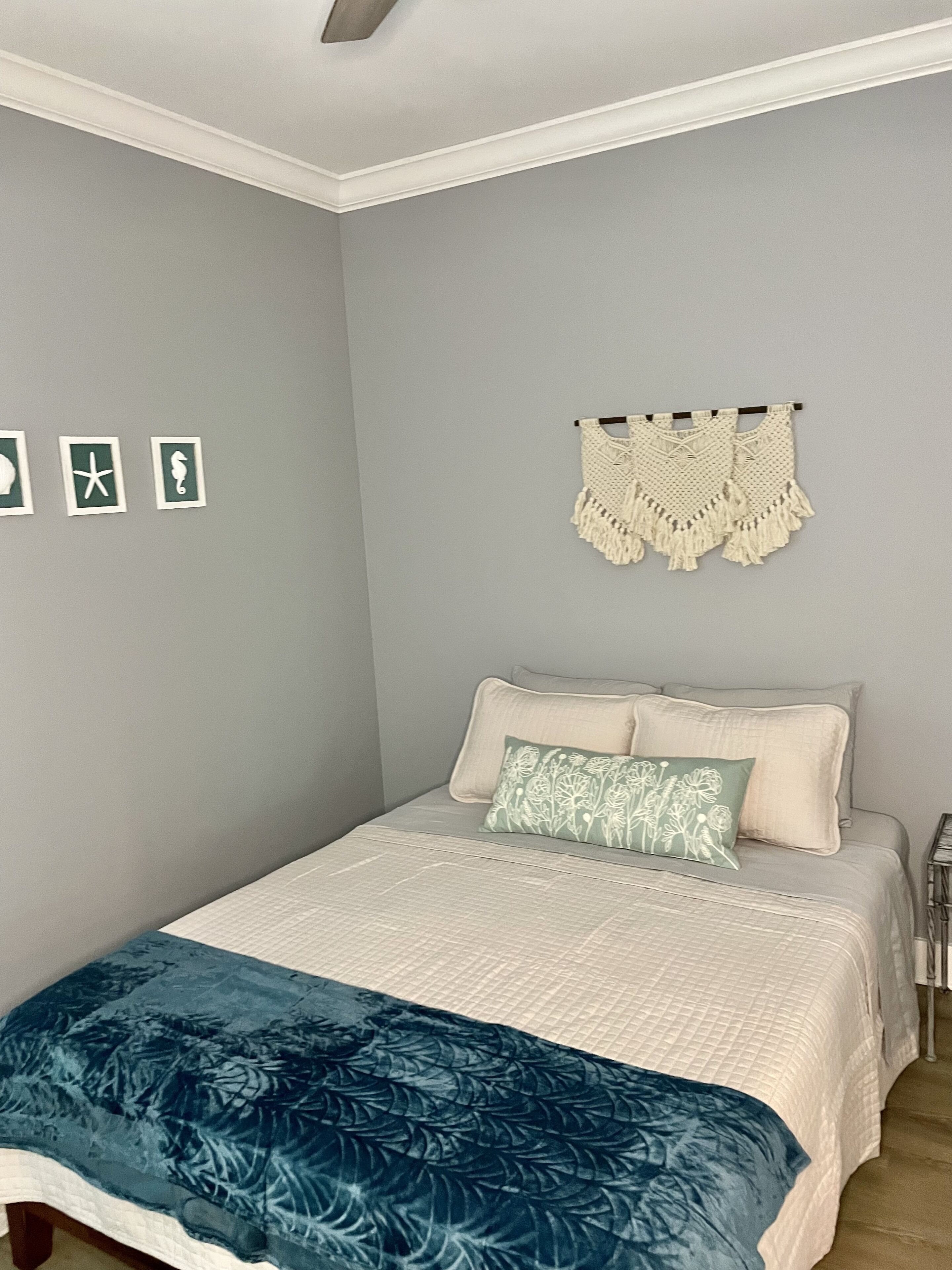A bedroom with a bed, pillows, a blanket, and wall decorations.