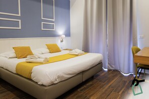 A neatly made bed with white and yellow bedding, a wooden floor, and a simple wall design. - Hotiday Room Collection - Napoli Botanique (Naples)
