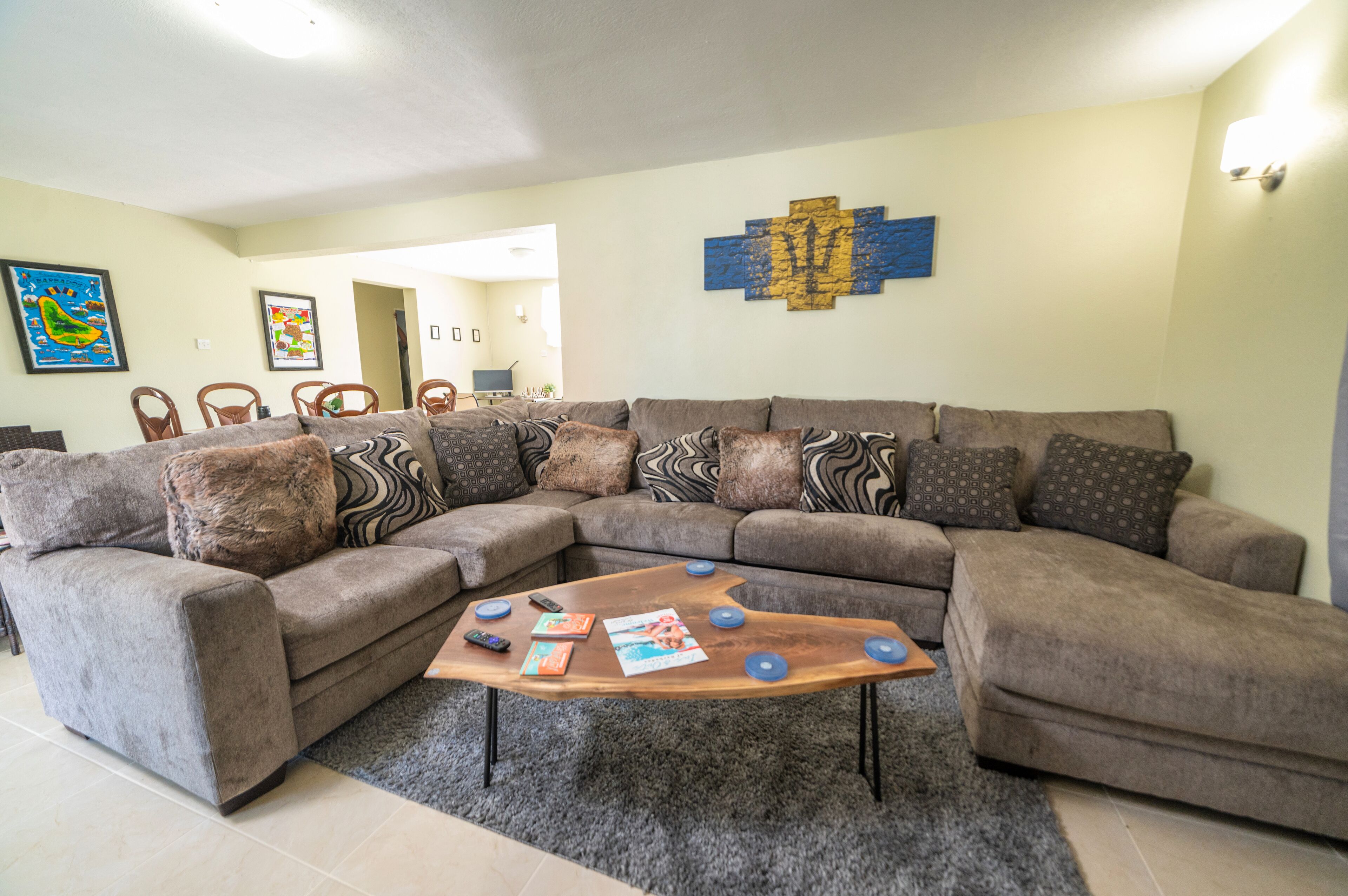 A living room with a sectional sofa, a coffee table, and wall art.