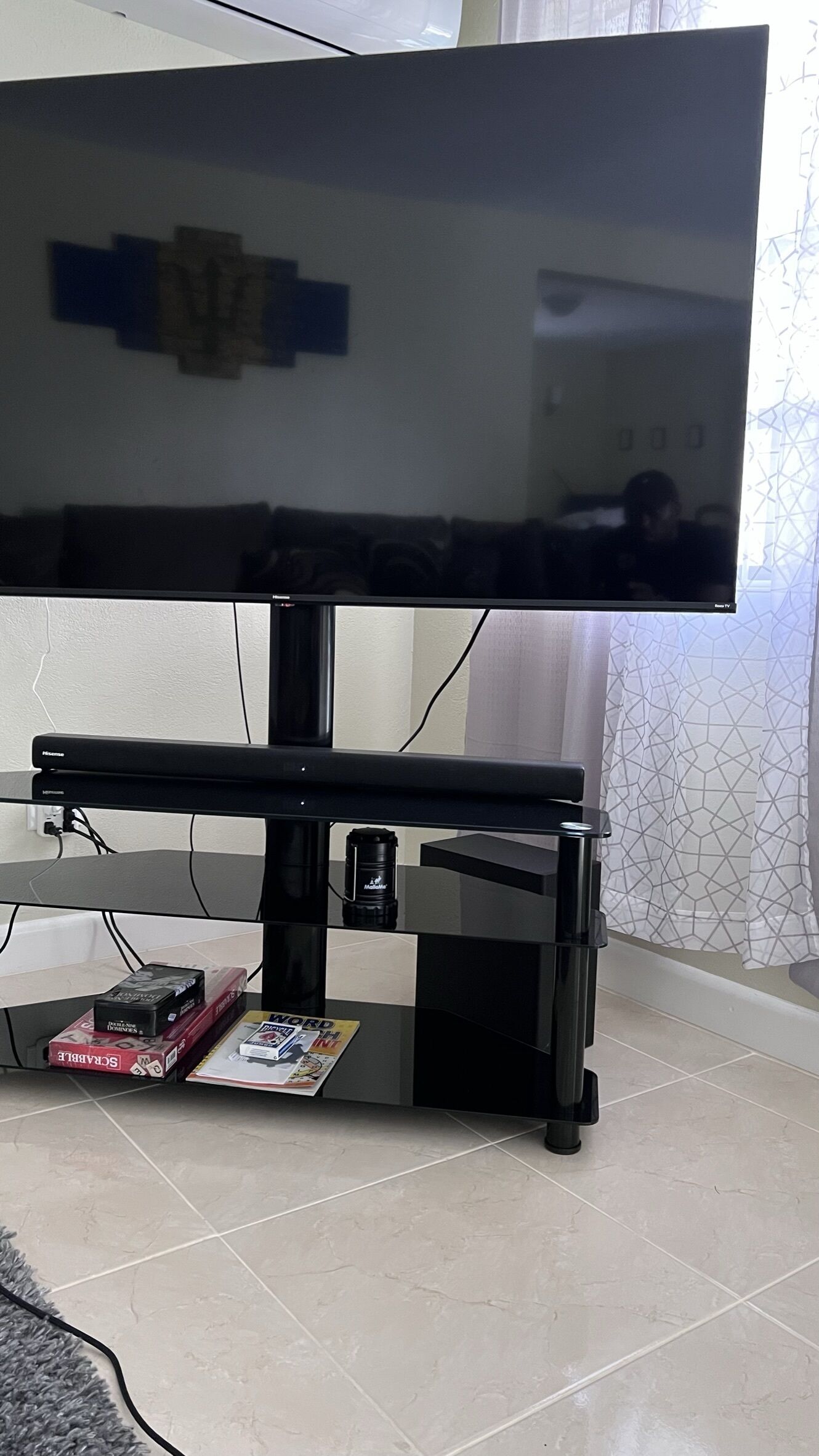 Uma televisão de tela plana em um suporte preto, com uma revista e uma câmera em cima.