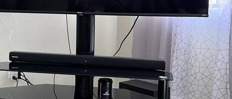 Uma televisão de tela plana em um suporte preto, com uma revista e uma câmera em cima.