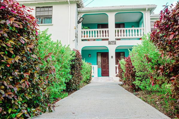 A two-story building with a balcony, a sign reading "Maxwell Lodge," and a pathway flanked by bushes. - 3 Bedrooms in paradise w/fruit trees 3 mins-Oistins! (Oistins)
