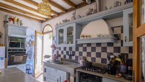 A kitchen with a checkered backsplash, a stove, and various kitchen utensils.