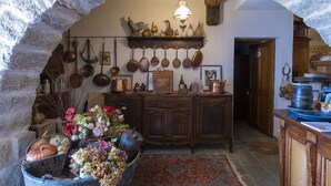 A rustic kitchen with stone walls, wooden cabinets, and a variety of kitchen utensils and decorations.