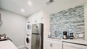 Una cocina moderna con refrigerador de acero inoxidable, lavadora integrada y salpicadero de azulejos.