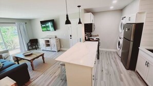 Una cocina moderna con una isla central, electrodomésticos integrados y una zona de comedor con sofá y mesa de centro.