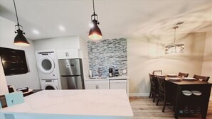Una cocina moderna con una isla central, electrodomésticos integrados y un comedor con una mesa y sillas de madera.