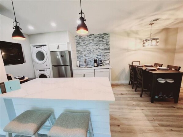 A modern kitchen with a central island, built-in appliances, and a dining area with a wooden table and chairs.