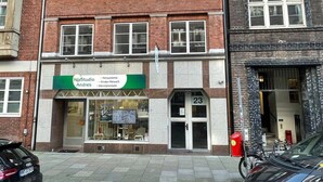 Un edificio con escaparate que indica "HörStudio Andres" y una puerta numerada con el número 23.