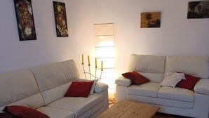 A living room with two white sofas, a wooden coffee table, and a wall-mounted lamp.
