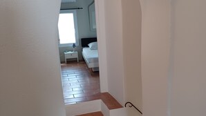 A staircase leading to a bedroom with a white bed, a nightstand, and a window.