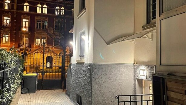 A narrow alleyway with a tiled pavement, a metal gate, and a building with a light fixture. - Studio 25 m² Côté Parc des Contades (Strasbourg)