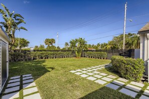 Un jardin bien entretenu avec une terrasse dallée, une végétation luxuriante et une clôture.
