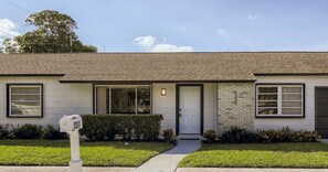 Une maison de plain-pied avec une porte d’entrée, deux fenêtres sur le côté gauche et une porte de garage sur le côté droit.
