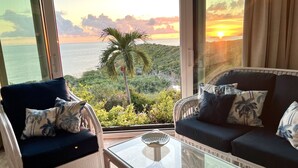 A balcony with a view of the sea and hills, furnished with a sofa and chairs, and a glass table. - ✩ Amazing ocean view (St Thomas)