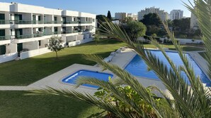 Un bâtiment moderne doté de nombreux balcons, d’une piscine et d’une pelouse bien entretenue.