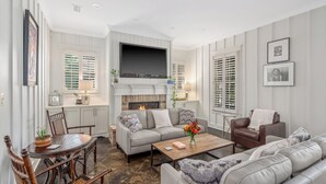 A living room with a fireplace, a sofa, a coffee table, and a television. - Emerson House Fairhope - Steps to Fairhope Pier, Downtown (Fairhope)