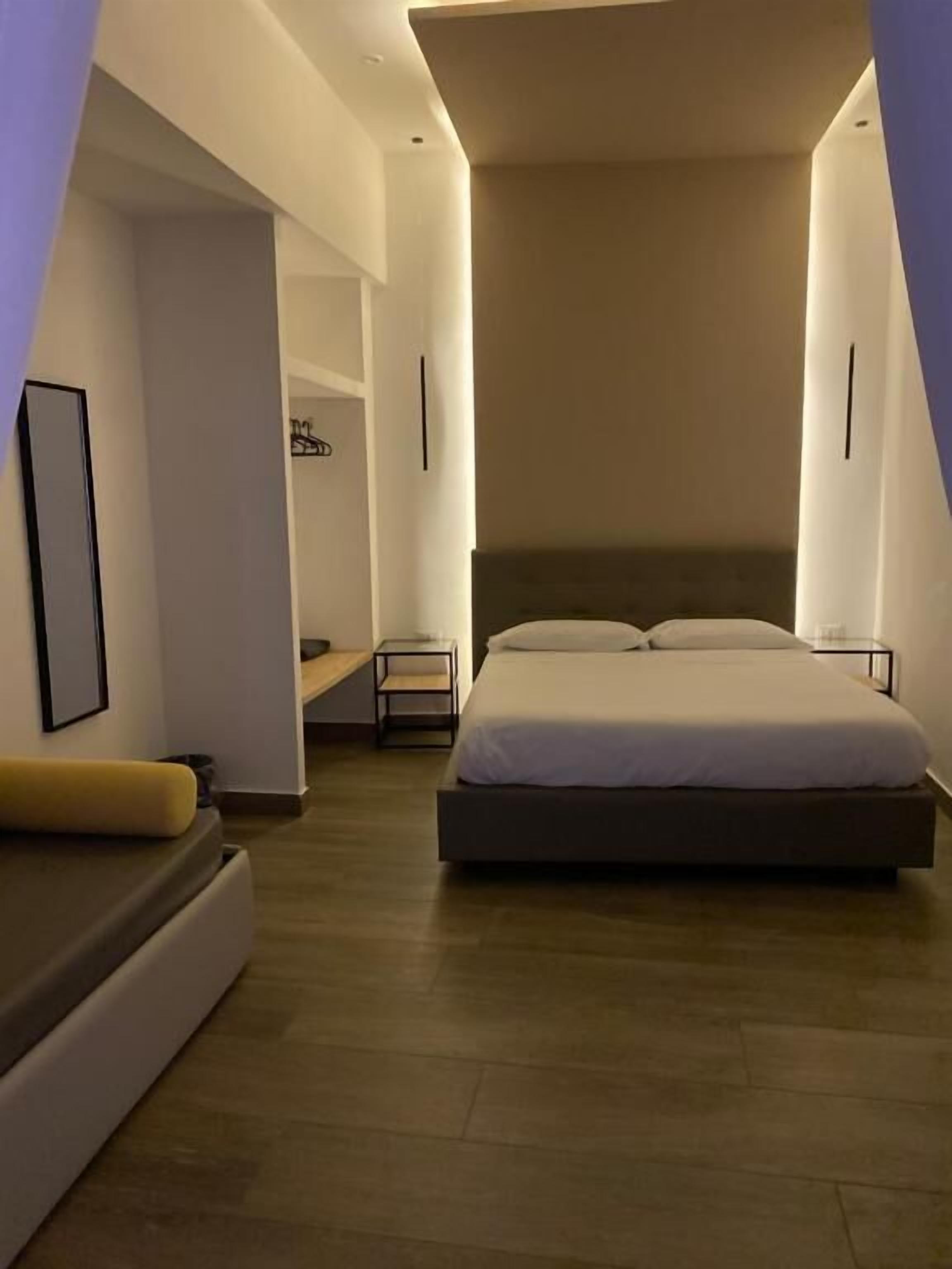 A modern bedroom with a large bed, a bedside table, a chair, and a small desk.