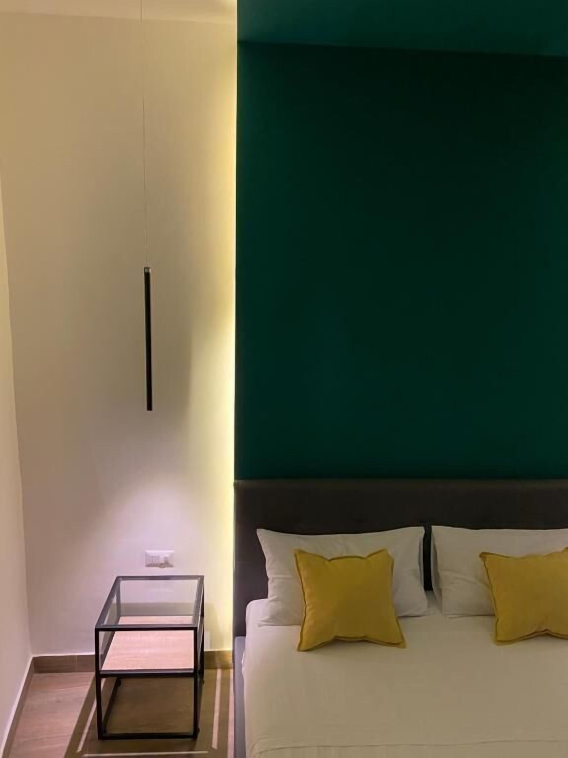 A bedroom with a bed, two pillows, a bedside table, and a nightstand.