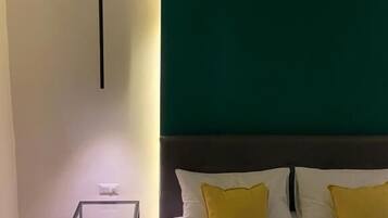 A bedroom with a bed, two pillows, a bedside table, and a nightstand.