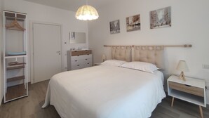 Un dormitorio con cama, mesitas de noche, armario y decoración en la pared.