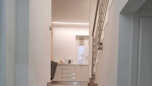 Una escalera conduce a una cocina de diseño moderno, con barandilla y una lámpara sobre los escalones.