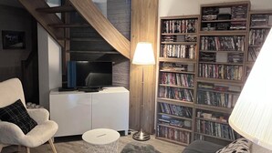 A modern living room with a staircase, a bookshelf, a sofa, a lamp, and a coffee table.