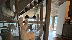 A wooden sculpture of a horse and rider in a spacious room with wooden floors and large windows.