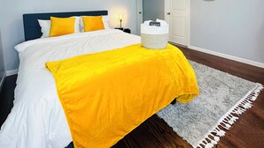 A bedroom with a bed, a bedside table, a mirror, and a wall with a motivational quote. - Modern 3BR 2BA• 5 Min to EWR • 30 Min to NYC  (Elizabeth)