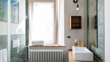 A modern bathroom with a glass shower enclosure, a white sink, and a wooden vanity.