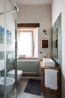 A modern bathroom with a glass shower enclosure, a white sink, and a wooden vanity.
