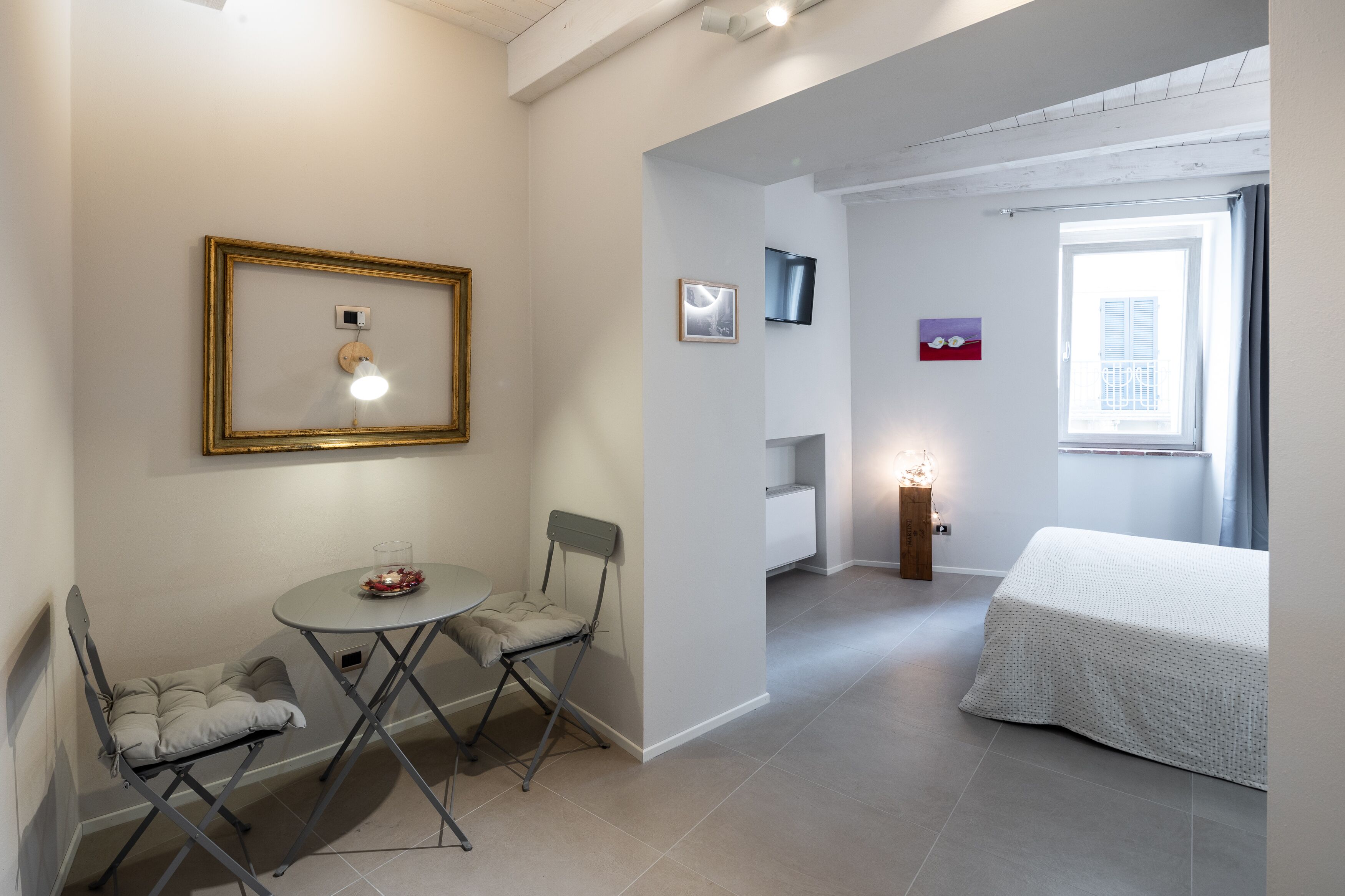 A room with a bed, a table with two chairs, a small desk, and a window with curtains.