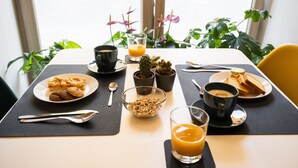 Una mesa de desayuno con diversas opciones de comida, como pasteles, cereales y jugo, además de tazas y una cuchara.