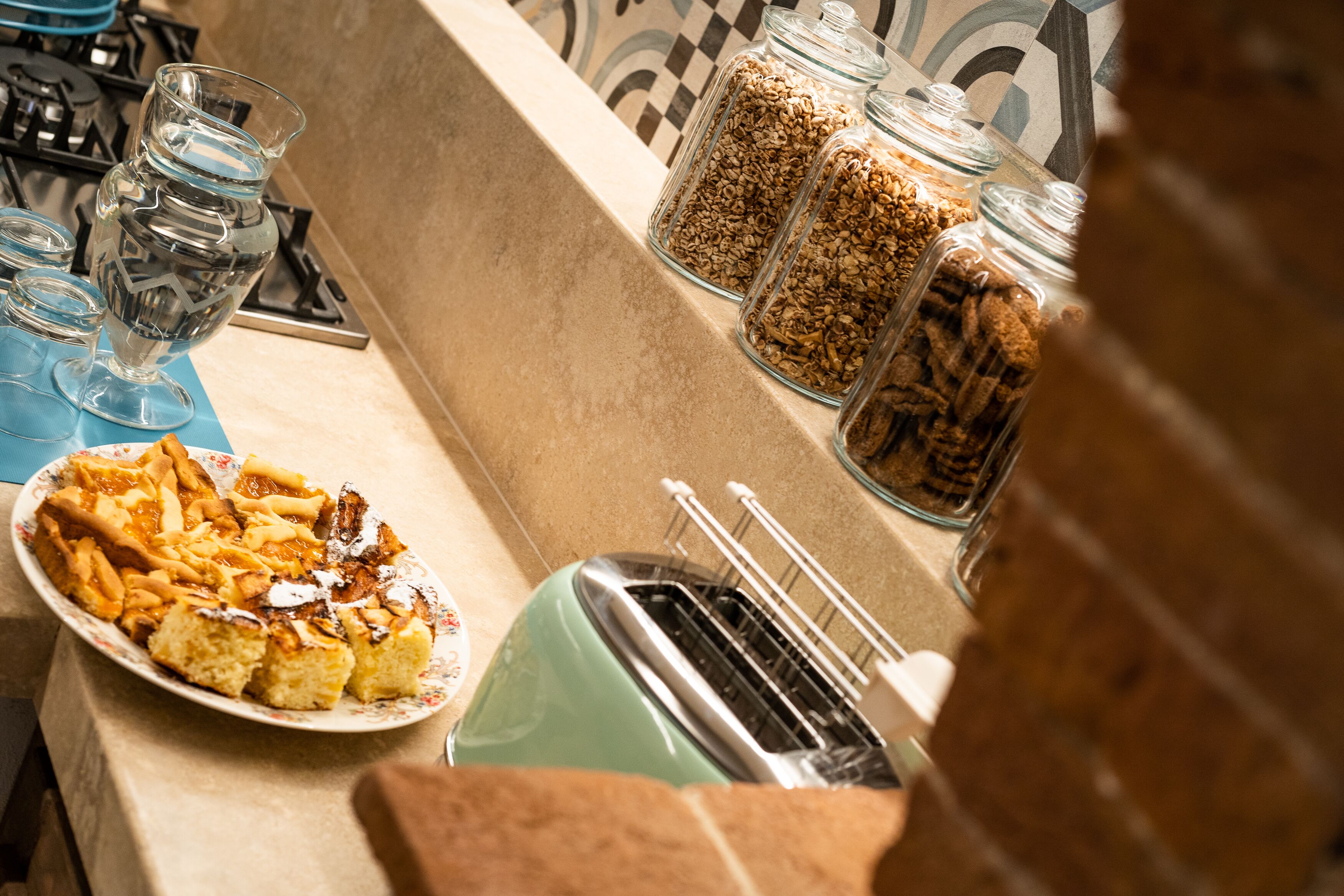 Eine Küchenarbeitsplatte mit einem Teller Essen, einem Toaster und Gläsern mit Granola und anderen Lebensmitteln.