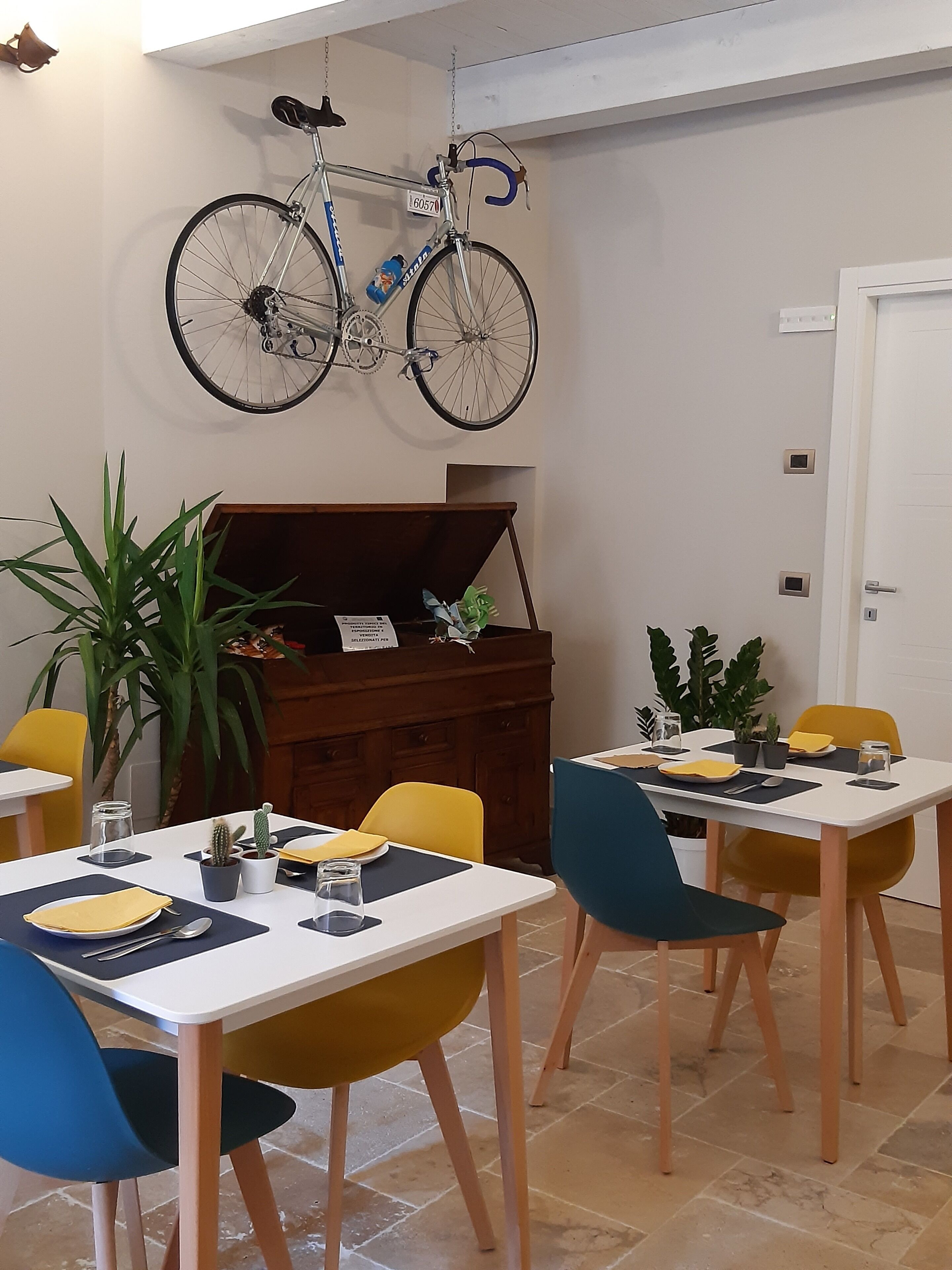 Un espace repas avec des tables, des chaises et un vélo accroché au mur.