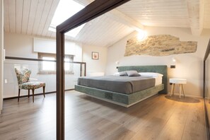 A bedroom with a bed, a chair, a lamp, and a stone wall. - A Casa di BiaGio B&B (Rapolano Terme)