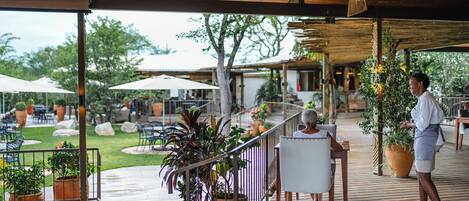 An outdoor patio area with wooden flooring, potted plants, and outdoor seating.