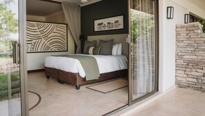 A bedroom with a large bed, a ceiling fan, and a view of the outdoors. - Insika Lodge (Victoria Falls)
