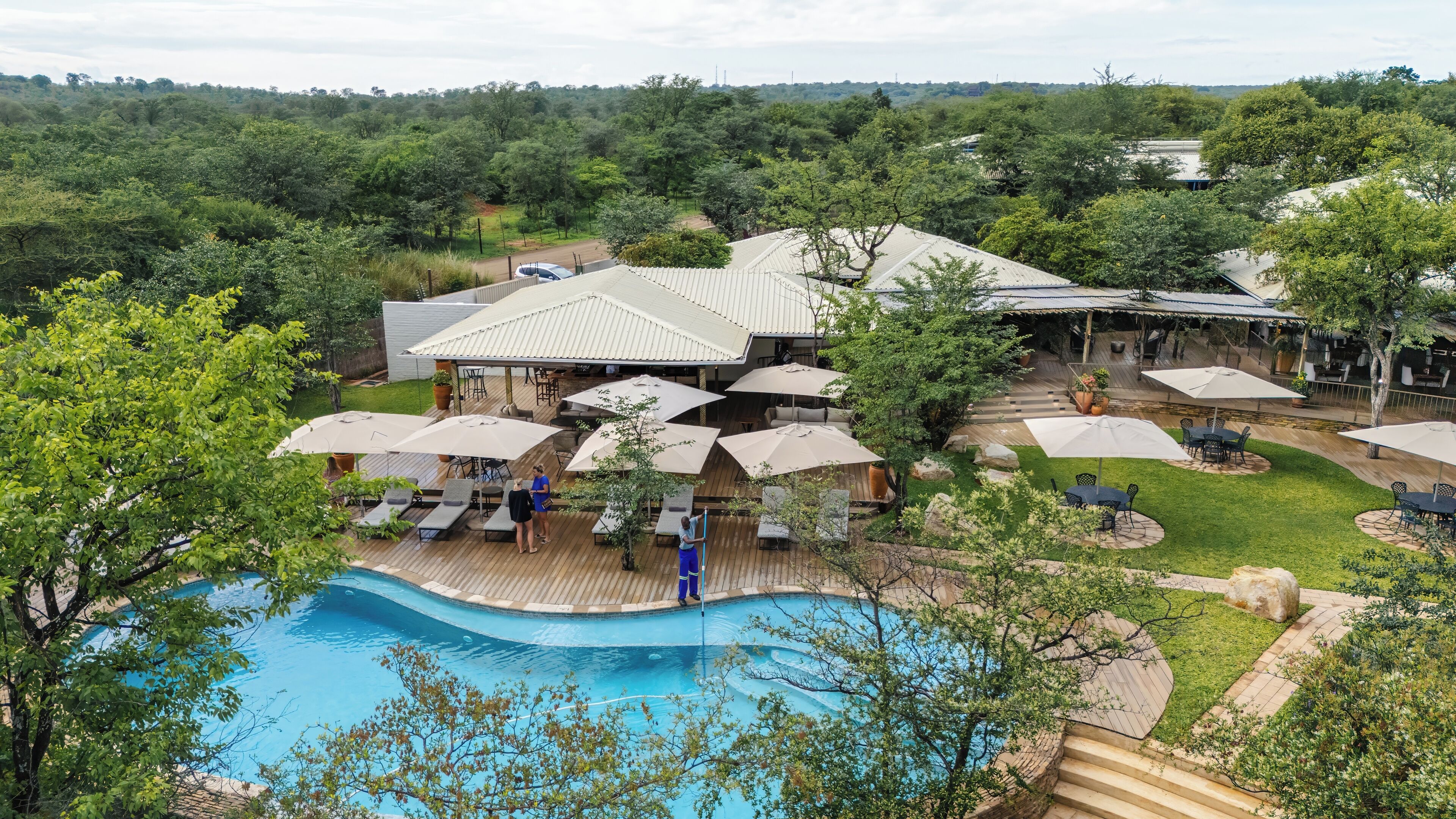 A resort with a swimming pool, outdoor seating, and a covered patio area.