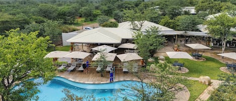 A resort with a swimming pool, outdoor seating, and a covered patio area.
