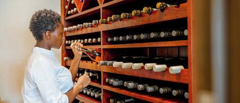A person organizing wine bottles on wooden shelves in a wine cellar.